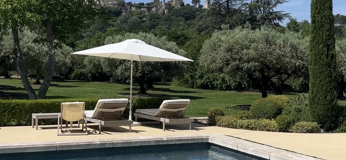 Private villa pool in Provence with sun loungers, olive trees and a perched village in the distance