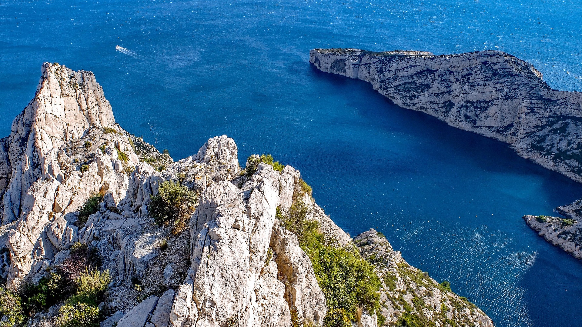Aerial view of a Marseille calanque with limestone cliffs plunging into deep blue Mediterranean water