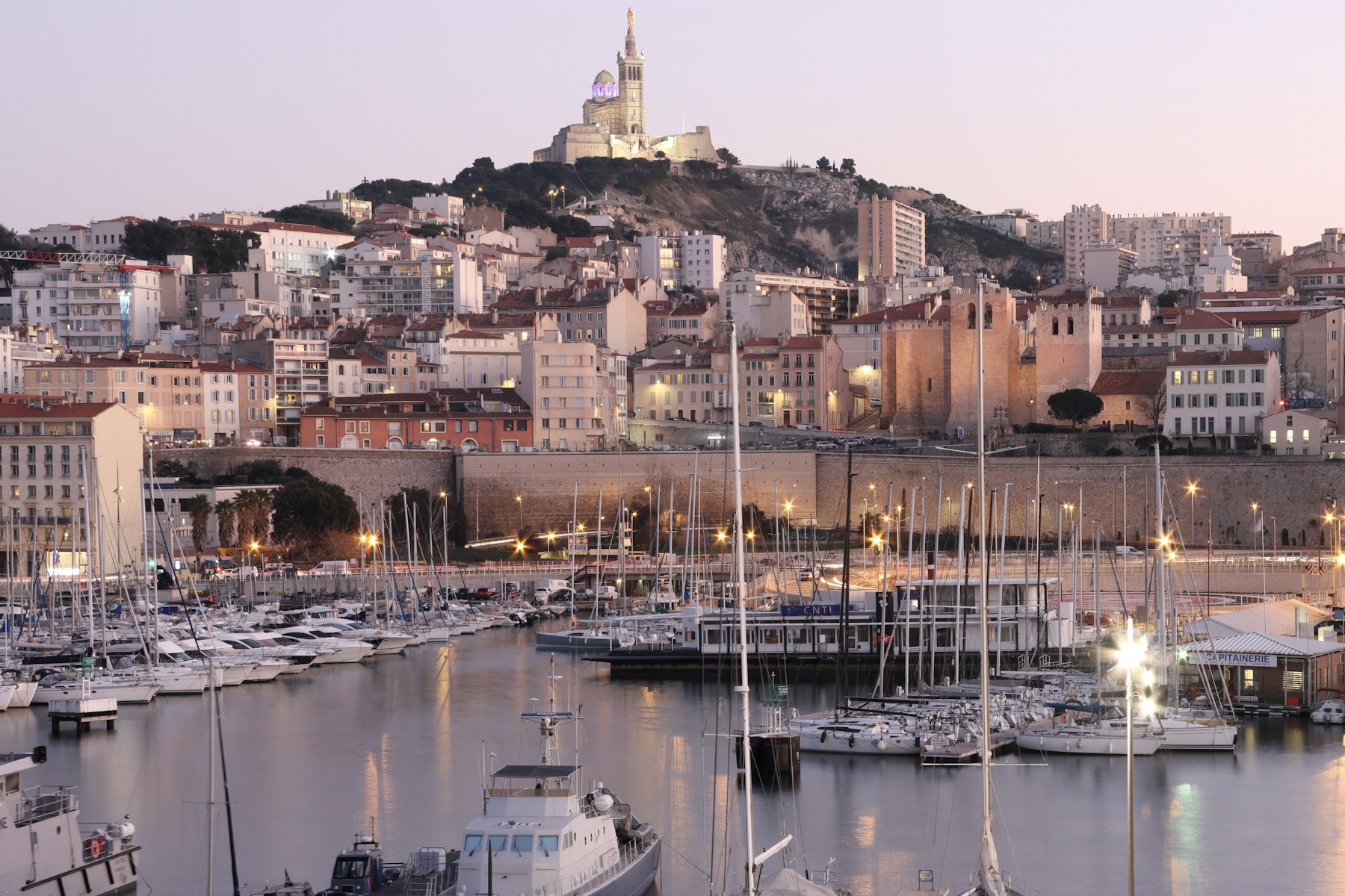 Marseille's Old Port at dusk with Notre-Dame de la Garde above the city